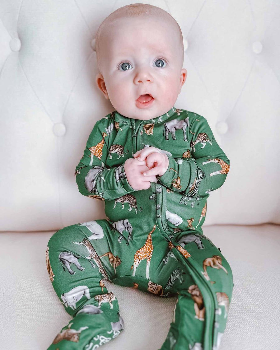 Baby wearing a green animal print onesie on a white background