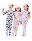 Three children wearing matching long-sleeve pajama sets with colorful animal and geometric prints, standing in a bedroom setting.
