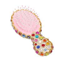 Pink hairbrush with colorful gemstones on a white background