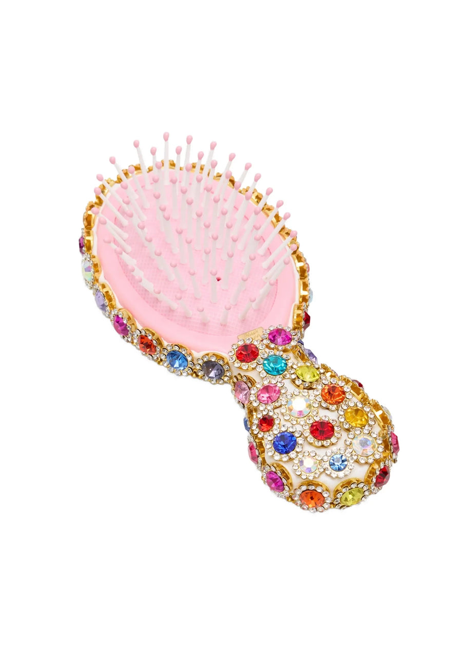 Pink hairbrush with colorful gemstones on a white background