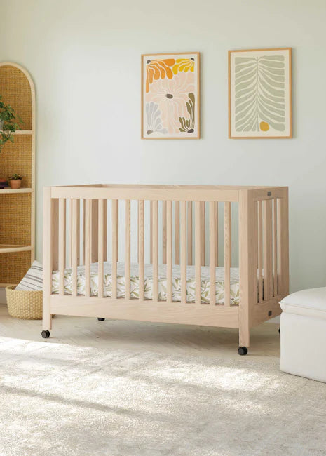 Nursery room with a wooden crib, white armchair, and ottoman.