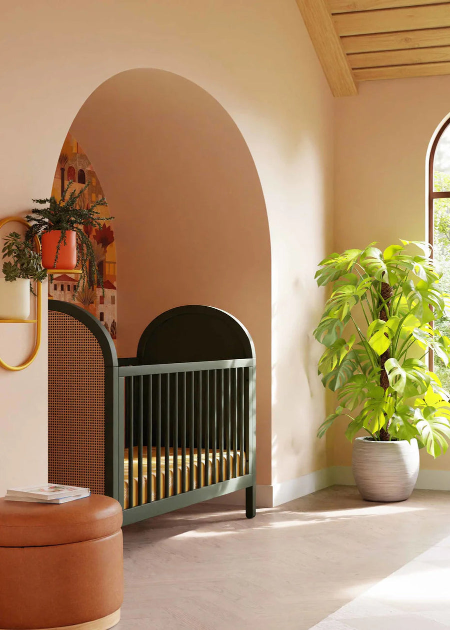 Modern nursery with a green crib, plant, and dresser.