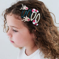 Child with colorful hair accessories in their hair against a plain background