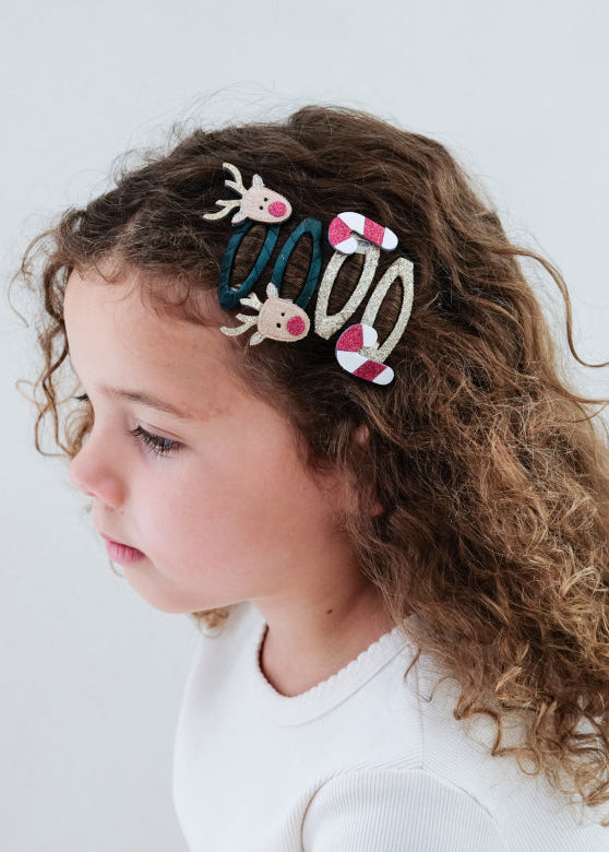 Child with colorful hair accessories in their hair against a plain background