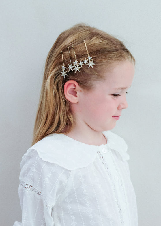 Young girl wearing star-shaped hair accessories against a plain background