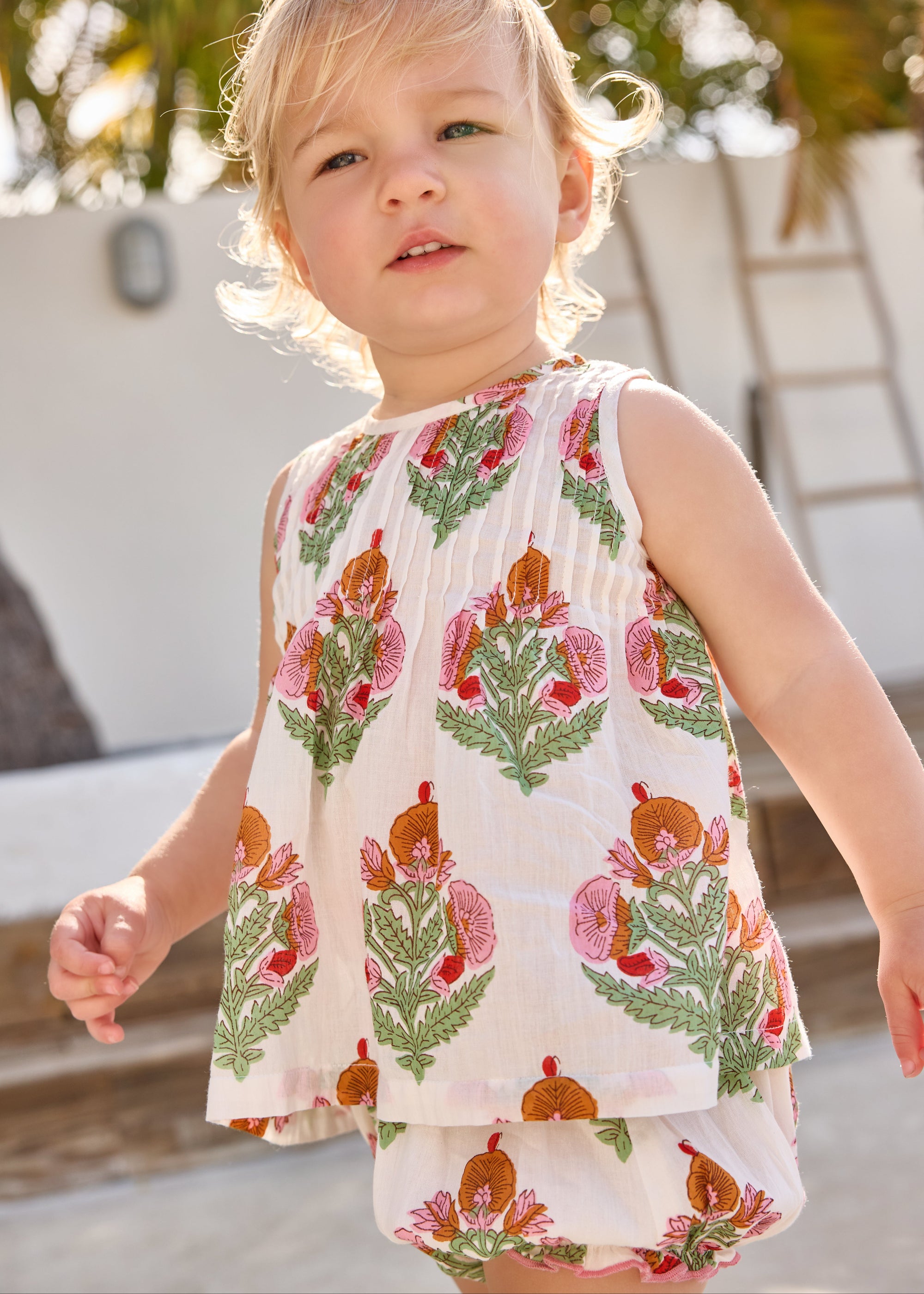 Child wearing a sleeveless top and shorts with floral pattern outdoors