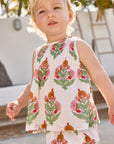 Child wearing a sleeveless top and shorts with floral pattern outdoors
