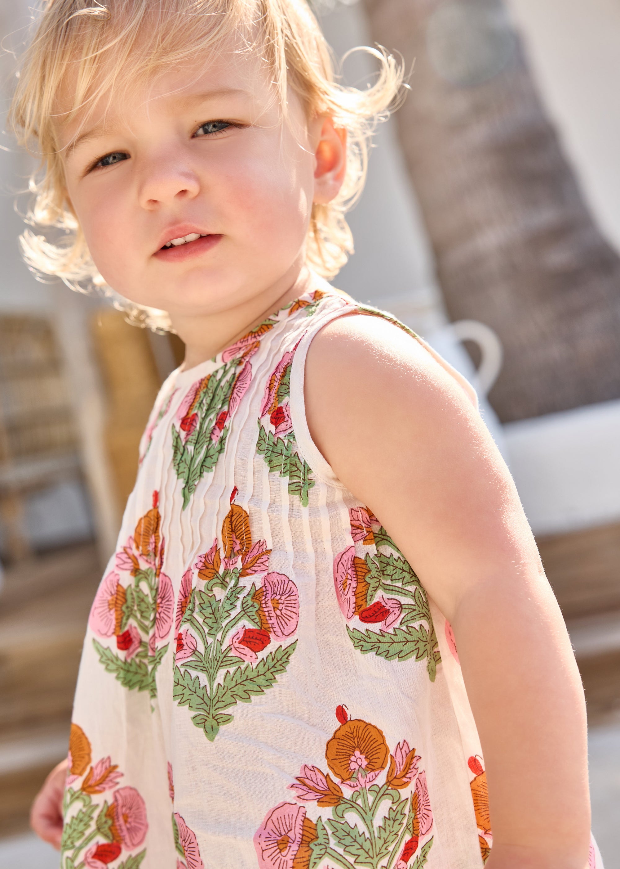 Child wearing a sleeveless dress with floral pattern outdoors