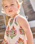 Child wearing a sleeveless dress with floral pattern outdoors