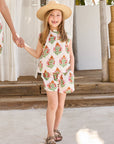 Woman and child holding hands in matching floral dresses on a tropical setting