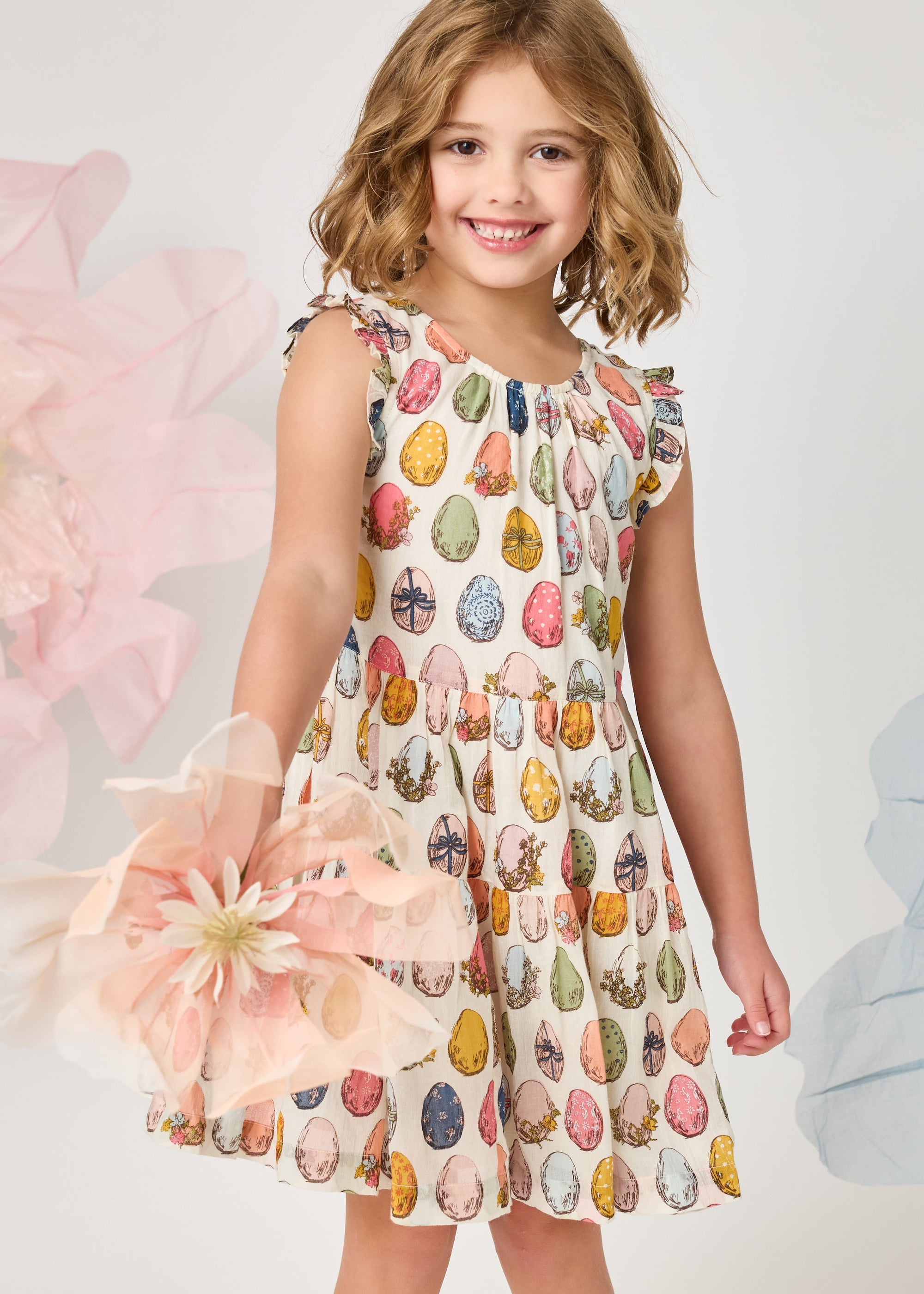 Young girl wearing a colorful dress with floral patterns against a light background