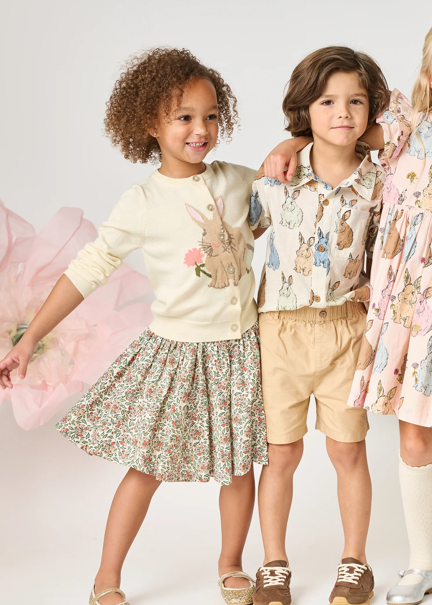 Three children wearing floral and patterned clothing with a soft, neutral background.