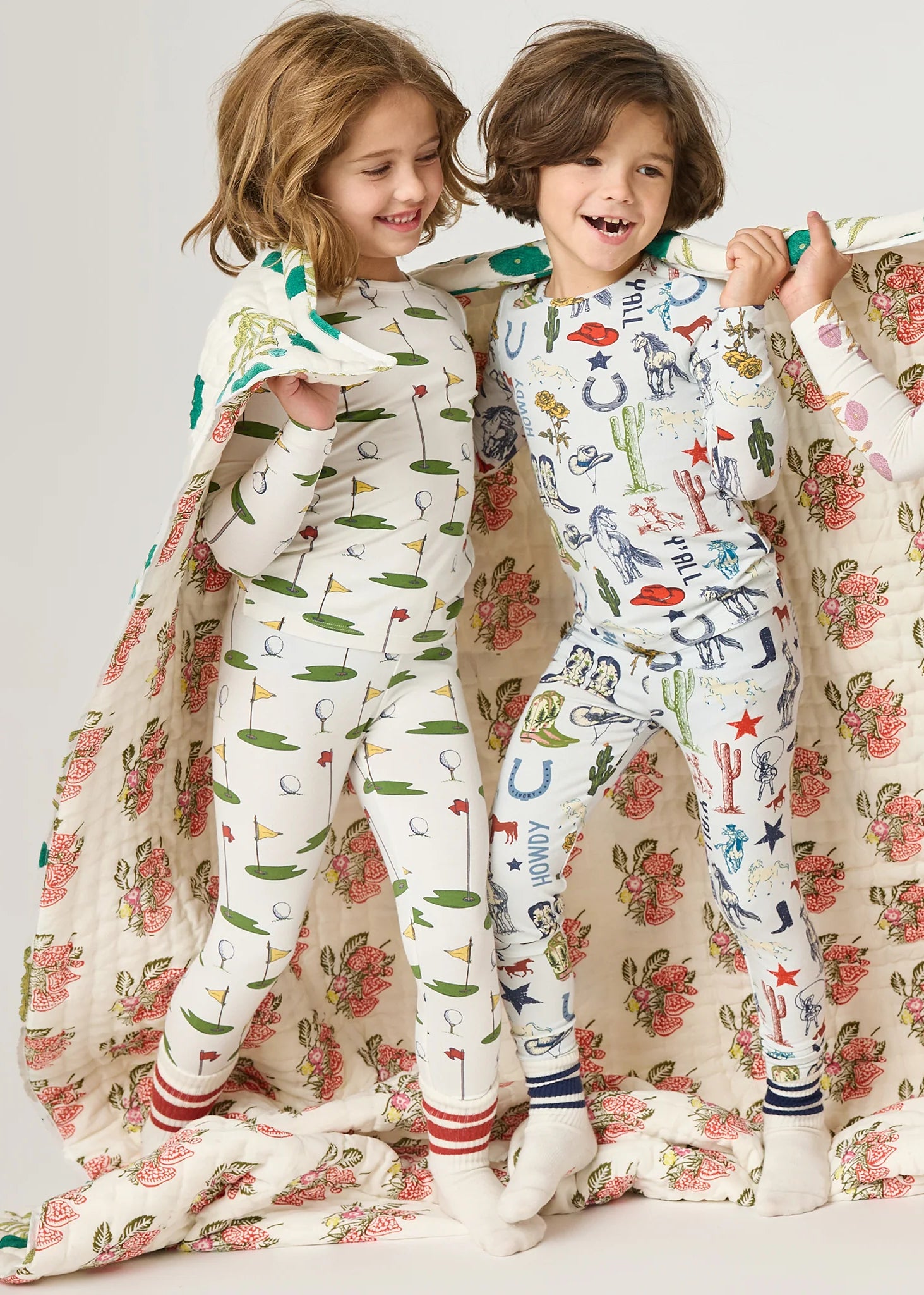 Two children in pajamas with a floral pattern on a plain background