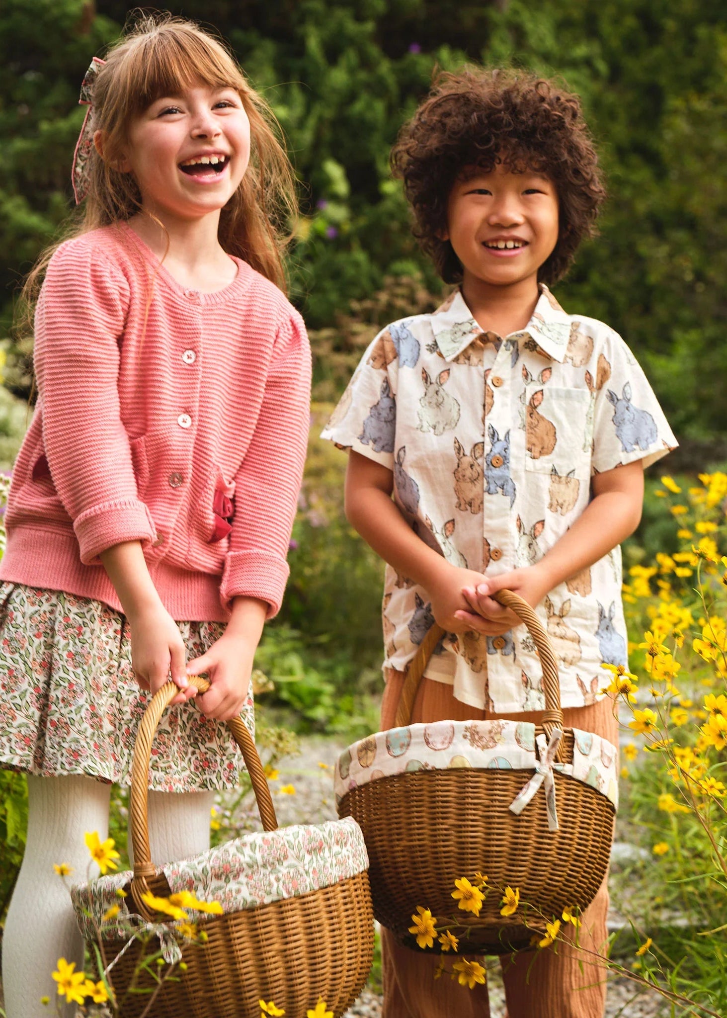 Two children standing in a field of flowers with wicker baskets.