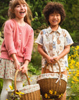 Two children standing in a field of flowers with wicker baskets.