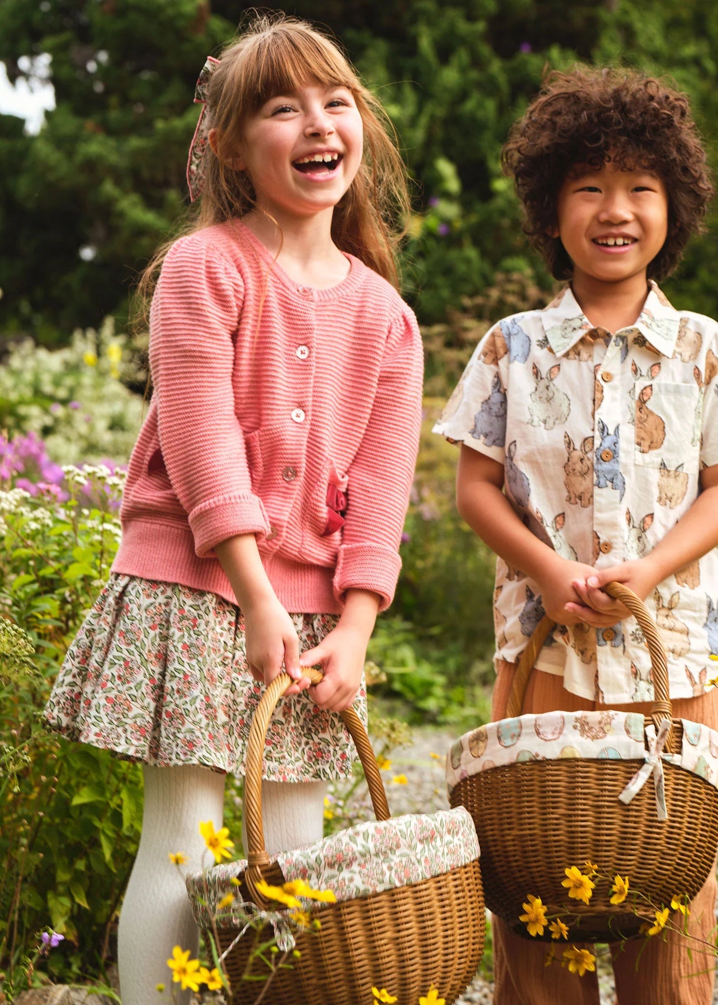 Two children standing in a field of flowers with wicker baskets.