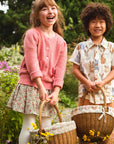 Two children standing in a field of flowers with wicker baskets.