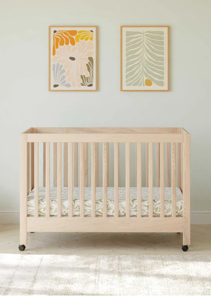 Wooden crib in a room with light-colored walls and a white couch.