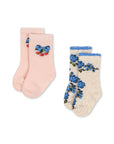 Two pairs of socks, one pink with blue floral design and red berries, the other beige with blue floral design.