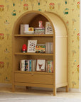 Wooden bookshelf with books and decor against a yellow wallpapered wall.