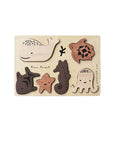 A wooden puzzle tray featuring six wooden pieces shaped as different ocean animals, including a whale, seahorse, crab, and others, arranged on a beige background.